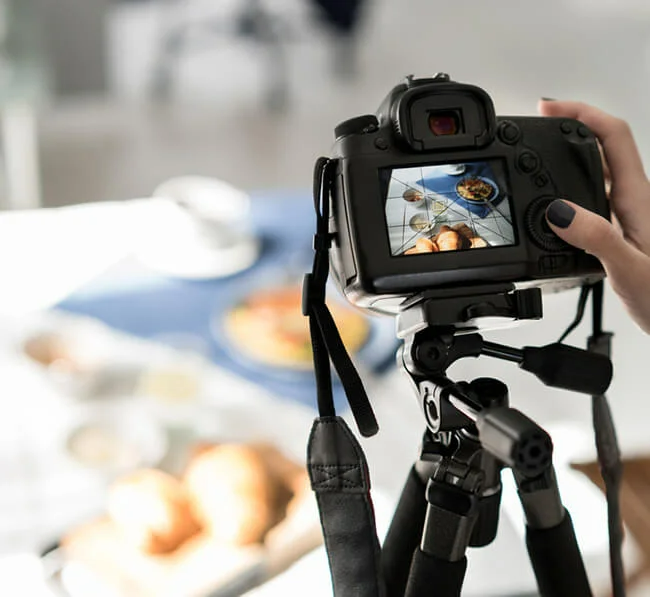 Photographer taking pictures of food and drinks on table with natural light