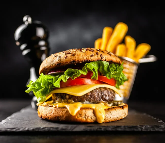 Grilled burger with chips and pepper shaker with black background