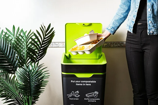 Person putting compostable food packing into Compost Connect bin