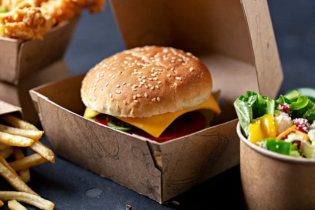 Burger, chips, and salad in eco-friendly takeaway containers