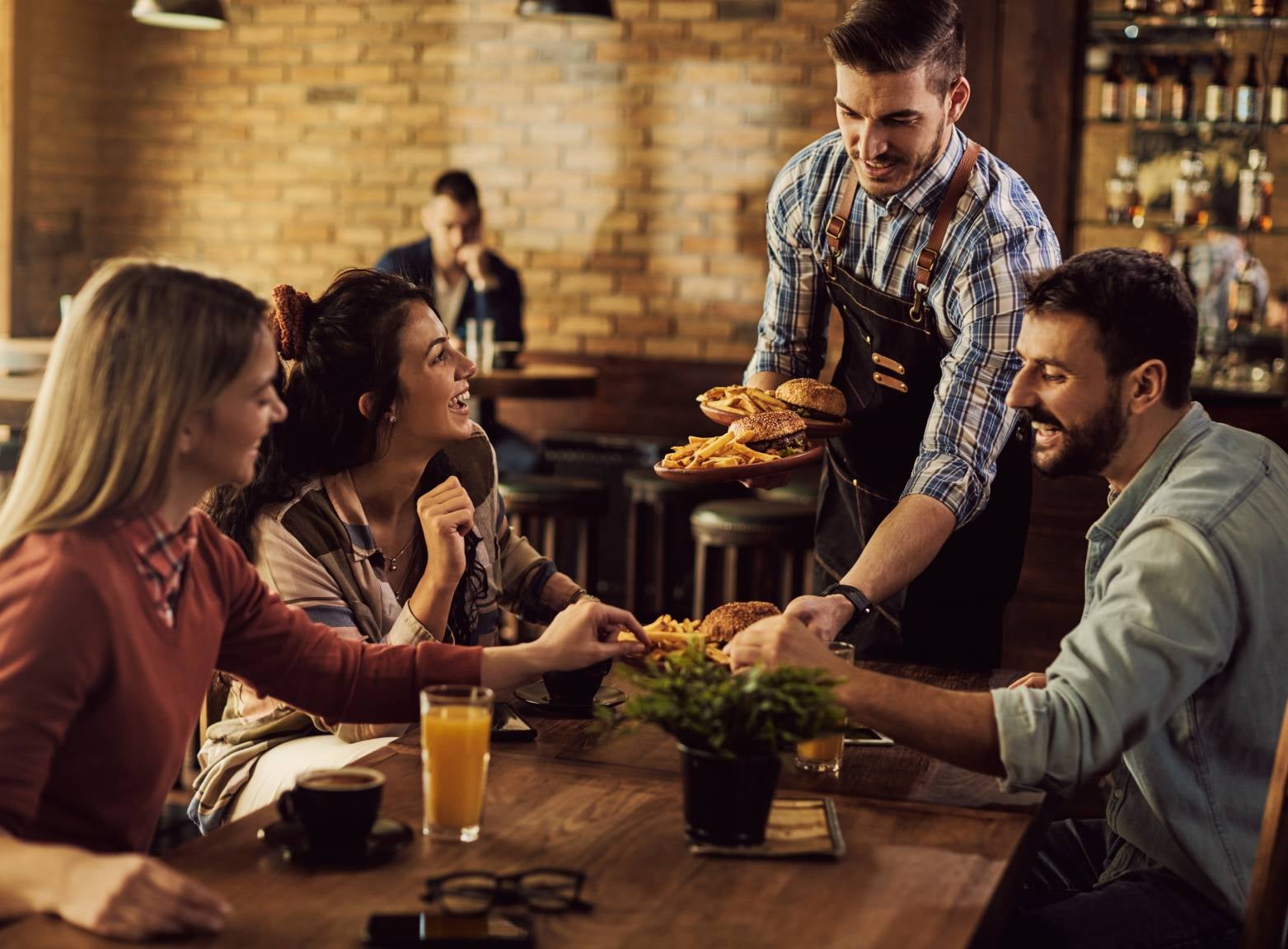 Food runner serves a group of customers in a restaurant