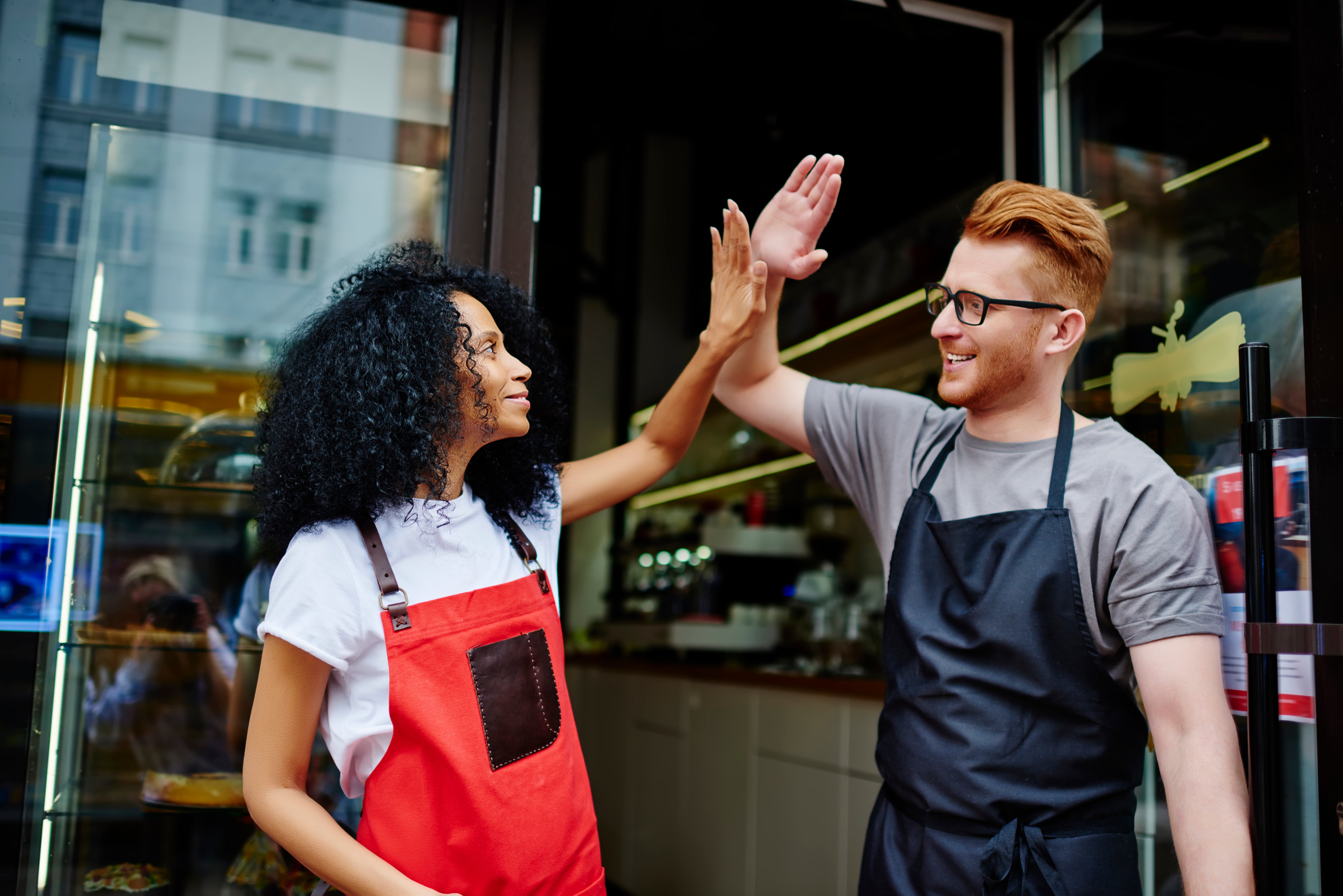 Male and female cafe workers high-fiving