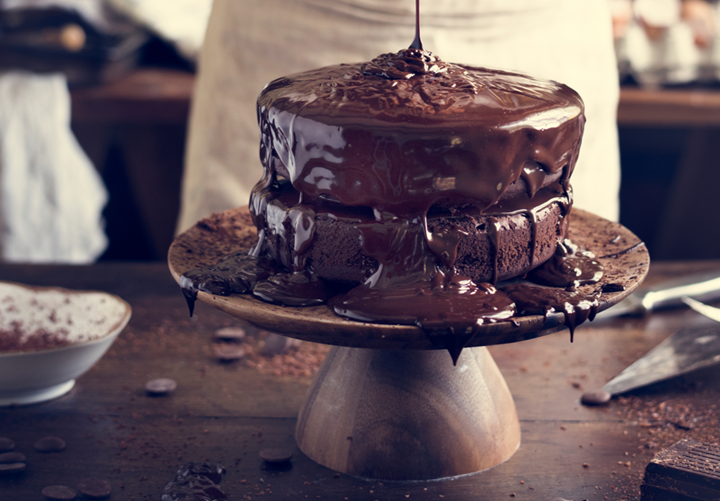 Brown, aesthetic cake with chocolate sauce being poured onto it