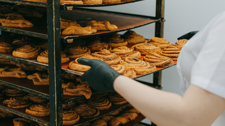 Woman pulling out a tray of scrolls at a bakery