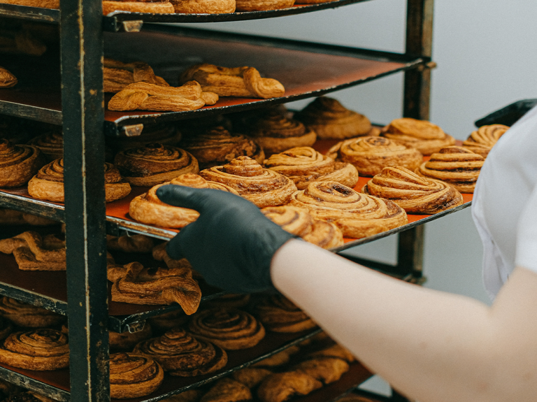 Woman pulling out a tray of scrolls at a bakery