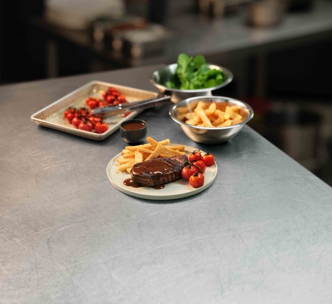 A plated porter house steak with hot chips and charred cherry tomatoes