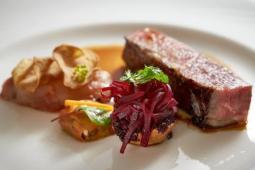 A plated porter house steak with hot chips and charred cherry tomatoes