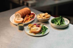 Golden brown roasted porchetta plated with colourful roasted dutch carrots and potatoes and brocollini with a jug of MAGGI go