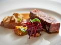 A plated porter house steak with hot chips and charred cherry tomatoes