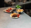 A plated porter house steak with hot chips and charred cherry tomatoes