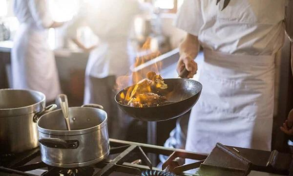 Chef using frying pan over gas stove